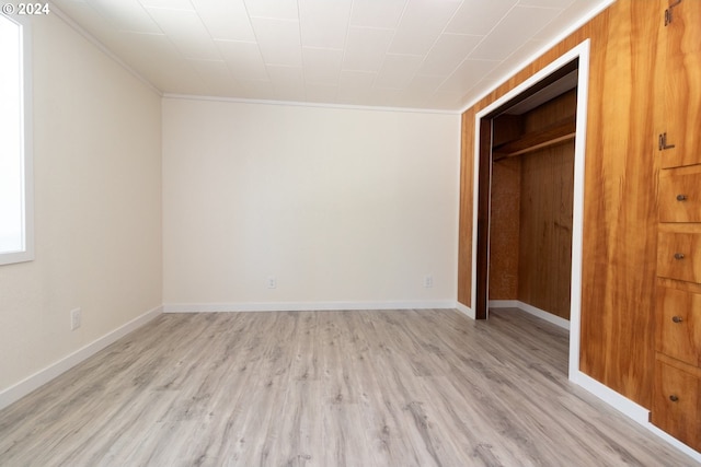 unfurnished bedroom featuring a closet, ornamental molding, and light hardwood / wood-style flooring