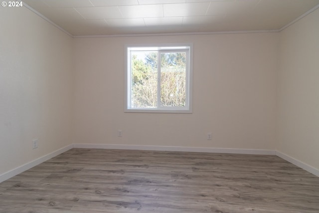 spare room with baseboards, ornamental molding, and wood finished floors