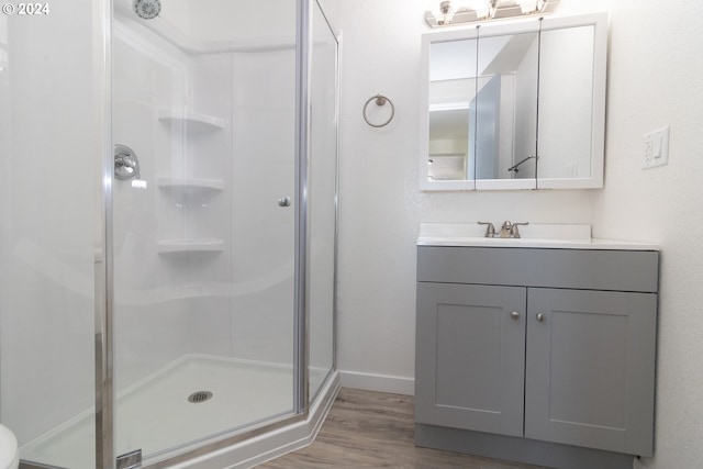 full bathroom featuring a stall shower, wood finished floors, vanity, and baseboards