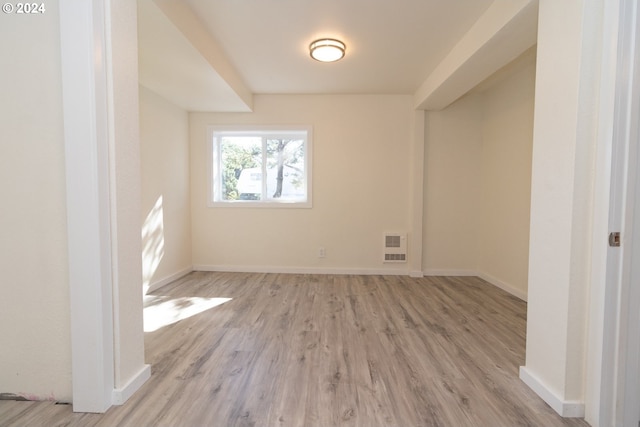 empty room featuring wood finished floors, baseboards, and visible vents