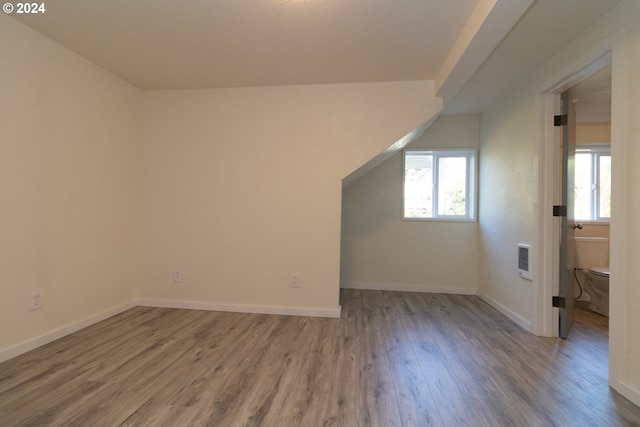 bonus room featuring wood finished floors, baseboards, and heating unit