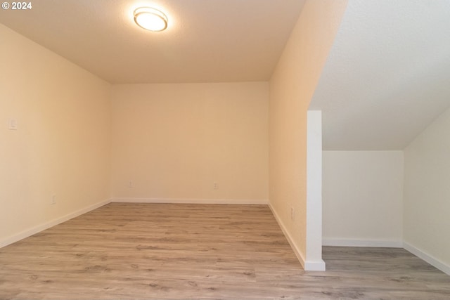 additional living space featuring baseboards and light wood-type flooring