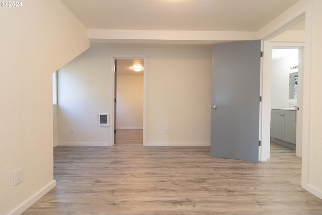 unfurnished room with light wood-style flooring, heating unit, and baseboards
