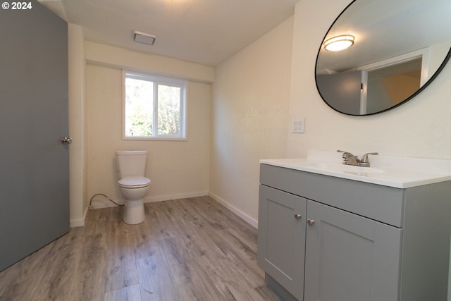 bathroom featuring vanity, baseboards, toilet, visible vents, and wood finished floors