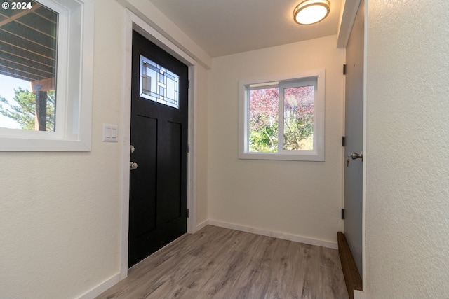 foyer with baseboards, light wood finished floors, and a textured wall