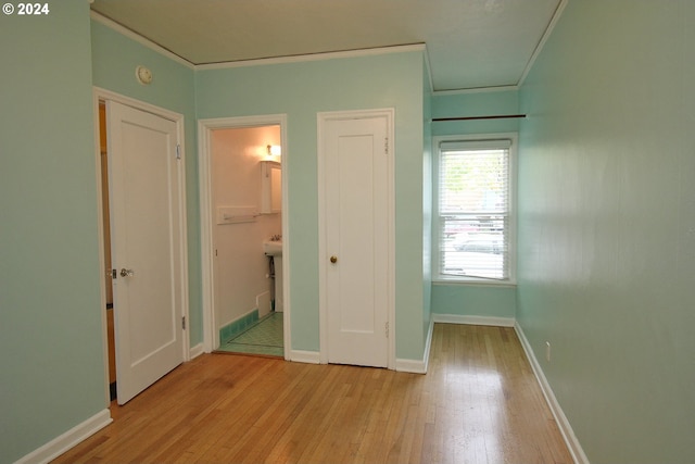 unfurnished bedroom featuring ornamental molding, ensuite bath, and light hardwood / wood-style floors