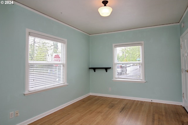 empty room with crown molding and light wood-type flooring