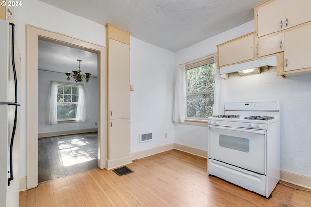 kitchen featuring gas range gas stove, an inviting chandelier, refrigerator, a textured ceiling, and light wood-type flooring