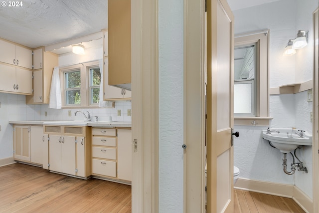 kitchen with light hardwood / wood-style floors, sink, and decorative backsplash