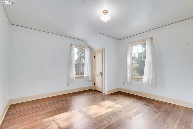 unfurnished room with hardwood / wood-style flooring and vaulted ceiling