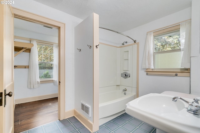 bathroom featuring hardwood / wood-style flooring, sink, a textured ceiling, and washtub / shower combination