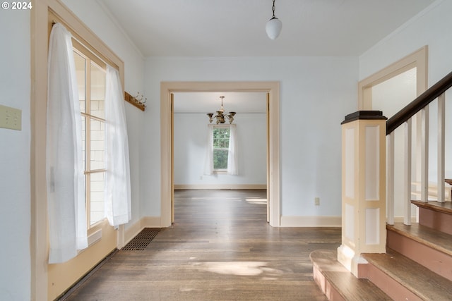 interior space with dark hardwood / wood-style flooring, crown molding, and an inviting chandelier