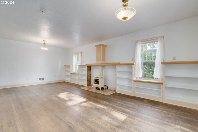 unfurnished living room featuring hardwood / wood-style floors, a healthy amount of sunlight, and a wood stove