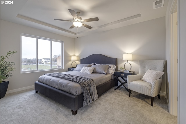 carpeted bedroom with a tray ceiling and ceiling fan