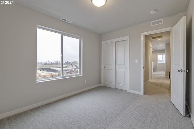 unfurnished bedroom with light colored carpet and a closet