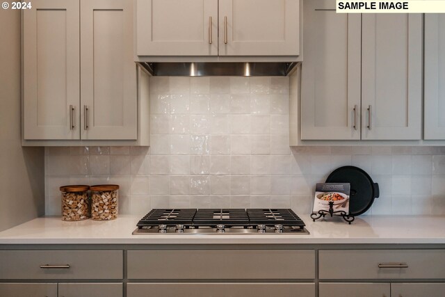 kitchen featuring stainless steel gas stovetop, extractor fan, tasteful backsplash, and gray cabinetry