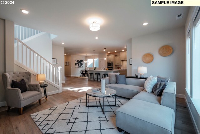 sitting room with built in shelves, a fireplace, and light hardwood / wood-style flooring