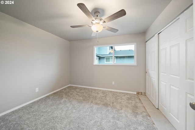 unfurnished bedroom featuring a closet, light colored carpet, and ceiling fan