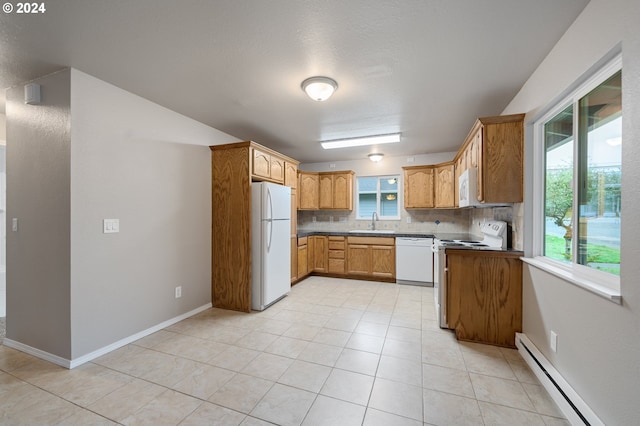 kitchen featuring a wealth of natural light, a baseboard radiator, backsplash, and white appliances