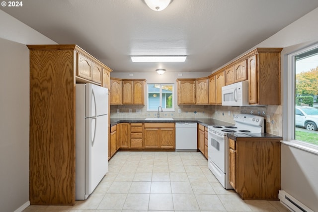 kitchen with baseboard heating, a wealth of natural light, white appliances, and tasteful backsplash