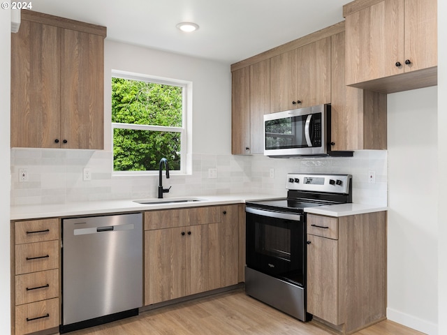 kitchen with light hardwood / wood-style floors, sink, backsplash, and appliances with stainless steel finishes