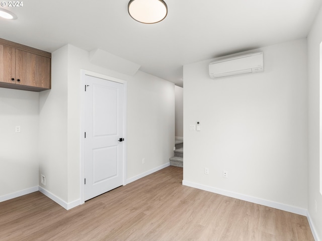 basement featuring a wall unit AC and light wood-type flooring