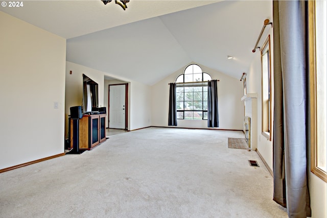 unfurnished living room with vaulted ceiling and light colored carpet