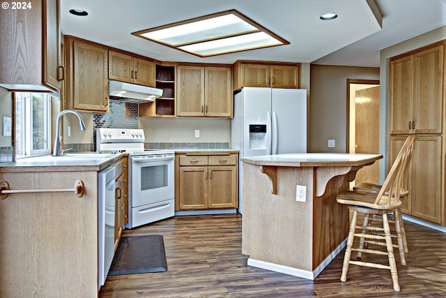 kitchen featuring white appliances, sink, a center island, dark wood-type flooring, and a breakfast bar area