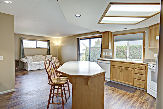 kitchen with white appliances, a healthy amount of sunlight, dark hardwood / wood-style flooring, and a kitchen island