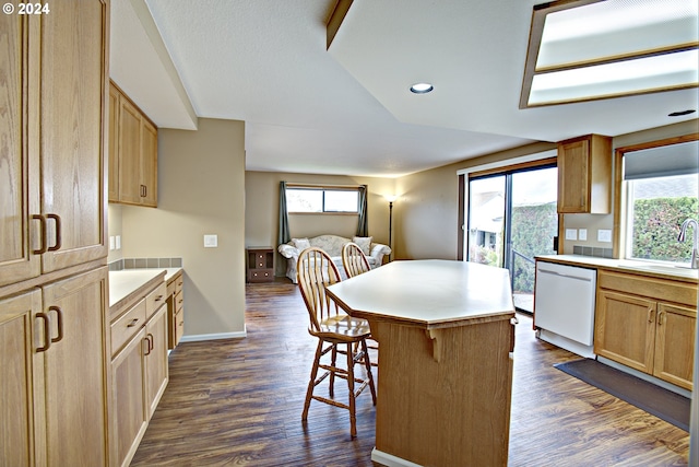 kitchen featuring dark hardwood / wood-style flooring, a breakfast bar area, a kitchen island, white dishwasher, and sink