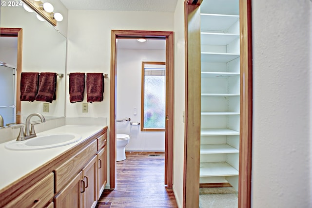 bathroom with vanity, toilet, a textured ceiling, and hardwood / wood-style floors