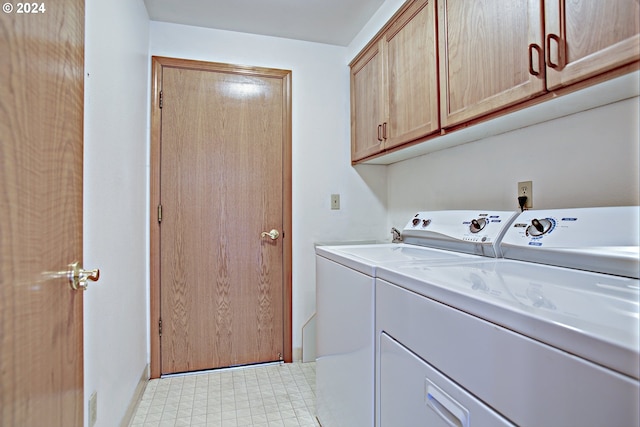 clothes washing area featuring cabinets and washer and dryer