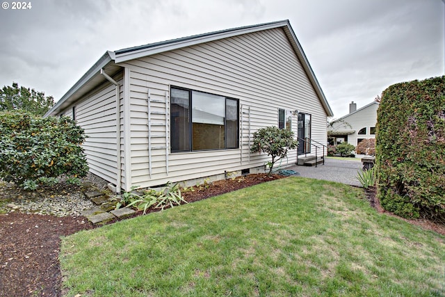 view of side of home with a patio area and a lawn