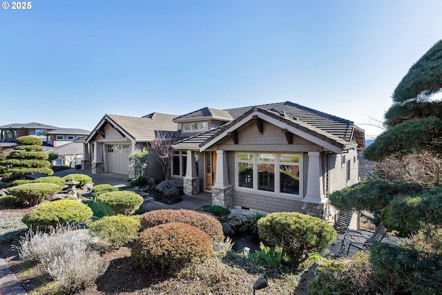 view of front facade featuring stone siding, a tile roof, and an attached garage