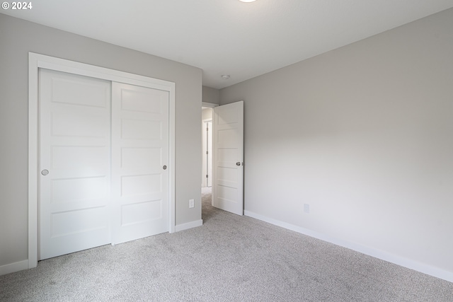 unfurnished bedroom featuring light colored carpet and a closet