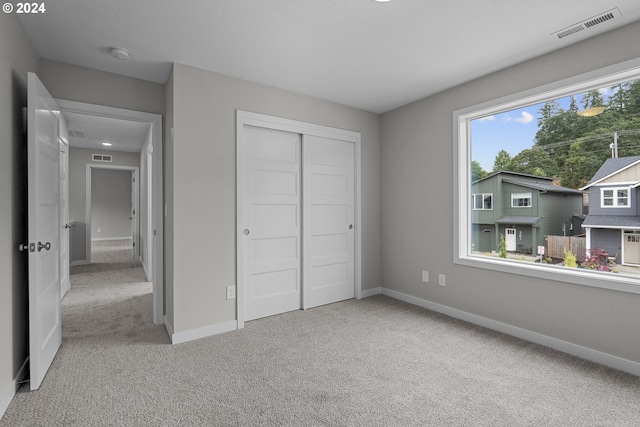 unfurnished bedroom with light carpet and a closet