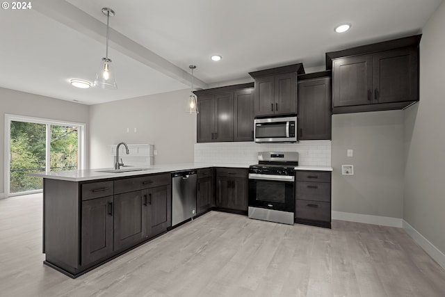 kitchen featuring stainless steel appliances, kitchen peninsula, decorative light fixtures, and sink