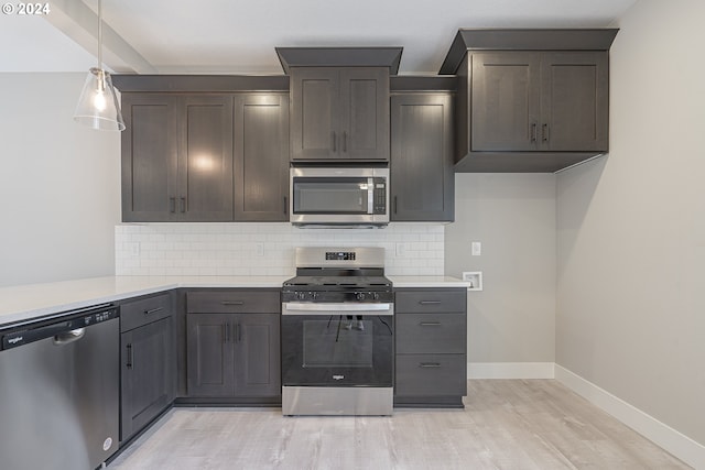 kitchen with hanging light fixtures, dark brown cabinets, appliances with stainless steel finishes, light hardwood / wood-style floors, and decorative backsplash