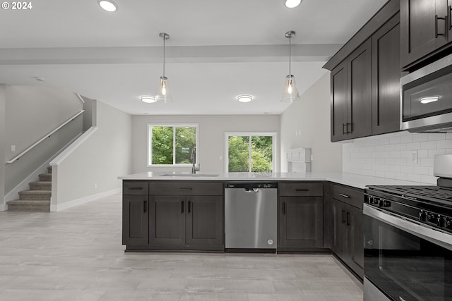 kitchen with appliances with stainless steel finishes, decorative backsplash, kitchen peninsula, and pendant lighting