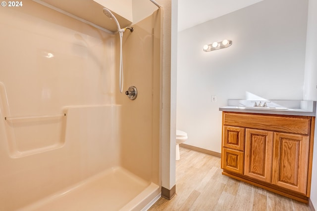 bathroom featuring walk in shower, wood-type flooring, toilet, and vanity