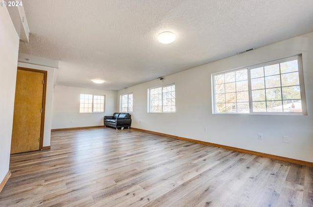 spare room featuring a textured ceiling and light hardwood / wood-style flooring