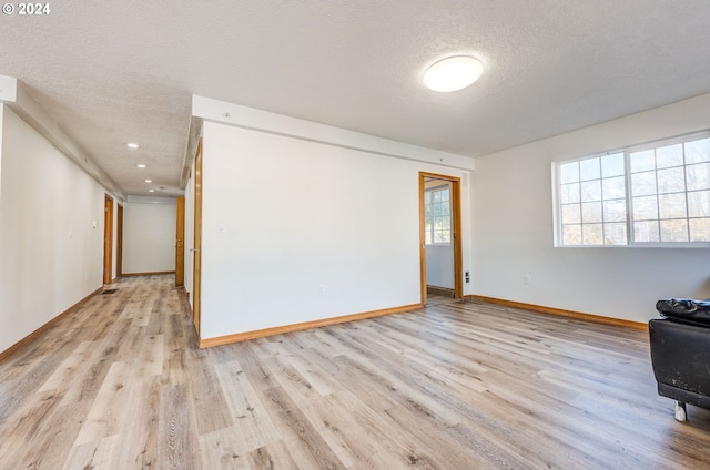 spare room with light hardwood / wood-style floors and a textured ceiling