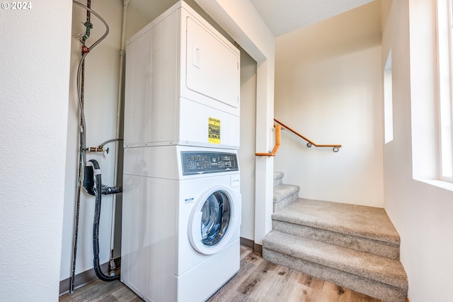 washroom featuring stacked washing maching and dryer and light hardwood / wood-style flooring