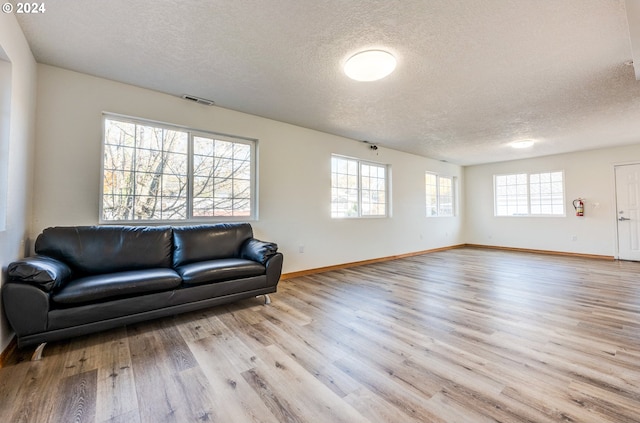 living room featuring light wood-type flooring and a textured ceiling