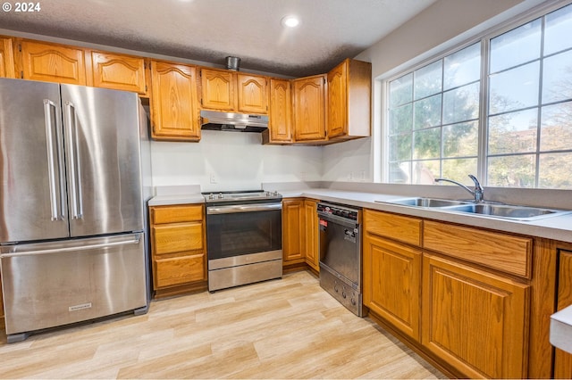 kitchen with a textured ceiling, light hardwood / wood-style floors, stainless steel appliances, and sink