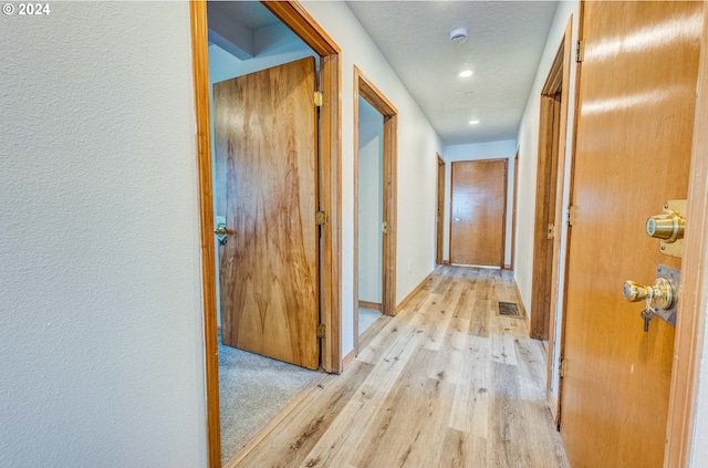 hall with a textured ceiling and light hardwood / wood-style flooring