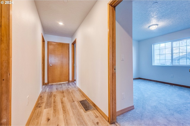 hallway featuring a textured ceiling and light hardwood / wood-style flooring