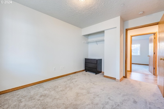 unfurnished bedroom with light carpet, a textured ceiling, and a closet