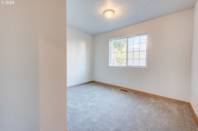 unfurnished room featuring carpet and a textured ceiling