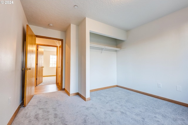 unfurnished bedroom with light colored carpet, a textured ceiling, and a closet